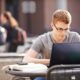 Young man sitting at a table outside with a laptop.